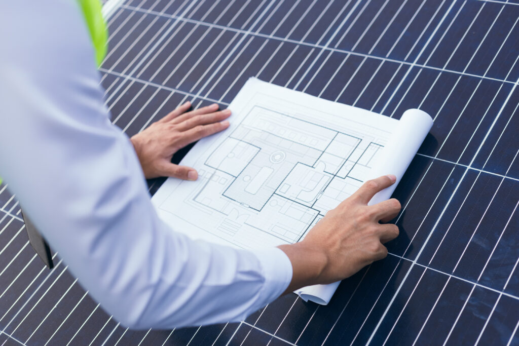 Engineer open blueprint of solar farm project on solar cells panel
